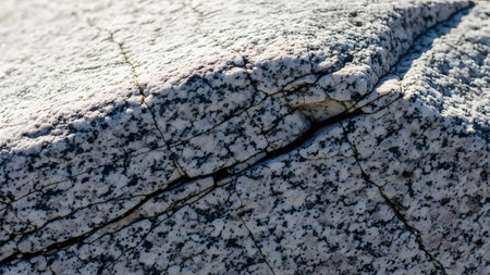 A detailed close-up texture of pink granite rock featuring a mix of black and white mineral speckles. The rough, natural stone surface highlights geological patterns and hardness.の素材