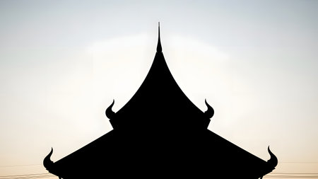 The dark silhouette of a traditional Asian temple roof with curved eaves and pointed finials stands against a pale twilight sky. The minimalist image captures the architectural elegance and spiritual serenity of the structure.の素材