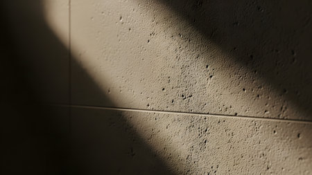 A close-up abstract view of a textured beige wall illuminated by a beam of light that creates a sharp diagonal shadow. The interplay of light and dark highlights the rough surface details and geometric composition.の素材