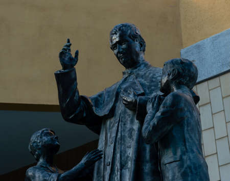Cagliari, Sardinia, Italy - August 20 2020: Bronze statue of Don Bosco with two children who pray...