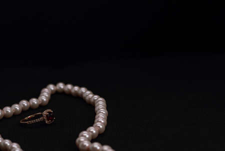 Golden Gem Ruby ring with small diamonds with pink pearl necklace on Black backgroundの写真素材