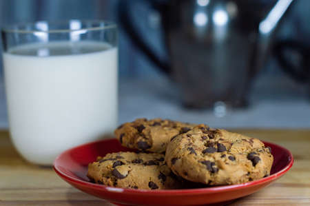 Chocolate Chip Cookies on red plate and Milk on wooden table - copy space area