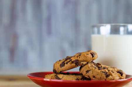 Chocolate Chip Cookies on red plate and Milk on wooden table - copy space area