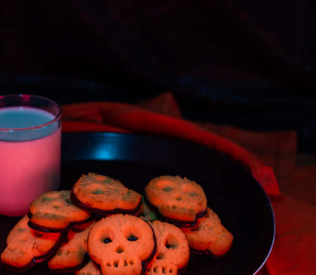 Halloween skull cookies with a glass of milk - black background copy space area - horror mood