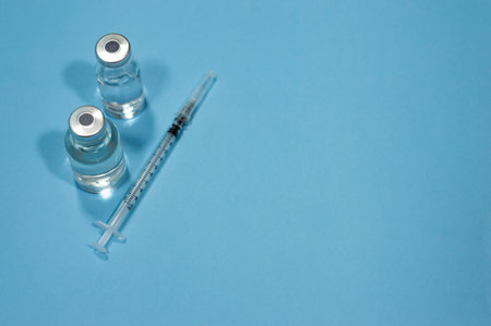 Medical equipment against coronavirus - syringe with vaccines on blue background with empty copy space areaの写真素材
