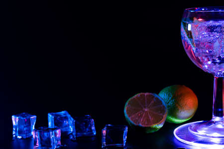 Gin Tonic cocktail in a glass with a lime and ice cubesの写真素材