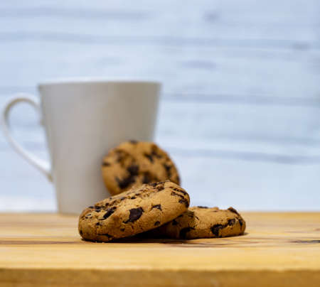 Chocolate chips cookies with a coffee cup on a wooden tableの写真素材