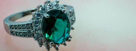 banner ring with precious stone, emerald gem set. pink marble backgroundの写真素材