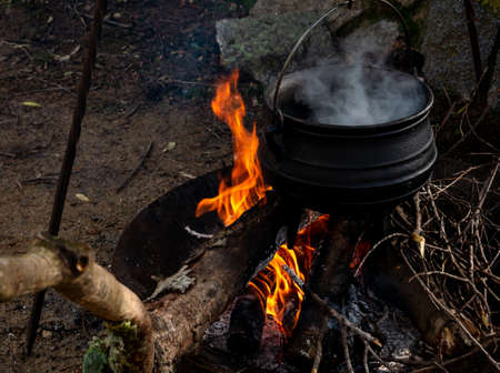 camp kitchen with cauldron, open steaming hot, metal on fireの写真素材