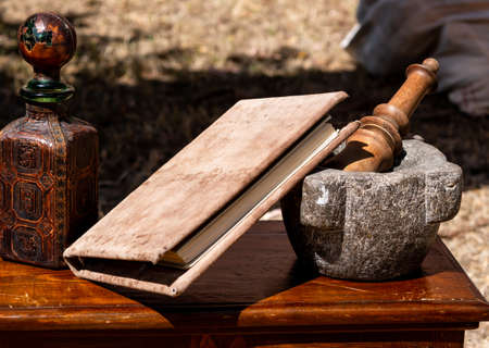 medieval reenactment - stone mortar and pestle on a wooden table with a bookの写真素材