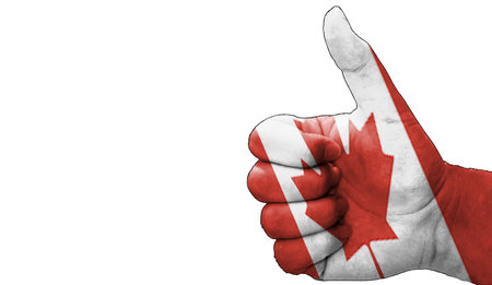 hand with thumbs up in approval with the Canadian flag painted. Image with empty white background copy space areaの写真素材