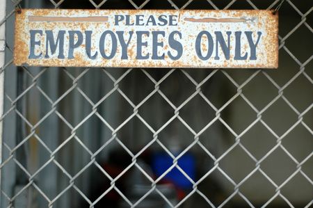 A Rusty 'Employees Only' Sign on a Chain Link Fence at an Abandoned Industrial Buildingの写真素材