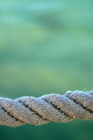 Nautical Image Of Some Weathered Harbor Rope Against A Green Ocean Background With Copy Spaceの写真素材