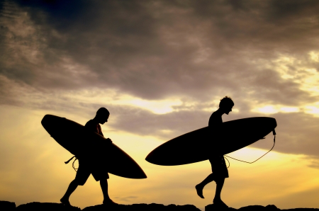 Vacation Silhouette Of Two Surfers Carrying Their Boards Home At Sunsetの写真素材