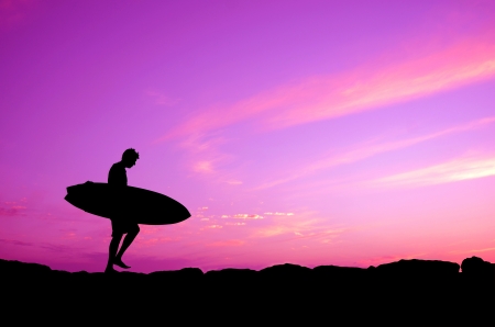 Vacation Silhouette Of A Surfer Carrying His Board Against A Purple Sunsetの写真素材