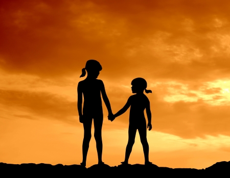 Silhouette Of Two Girls Holding Hands Against A Beautiful Sunsetの写真素材