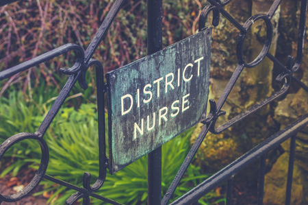 VIntage Style Photo Of A District Nurse Sign On A Garden Gateの写真素材