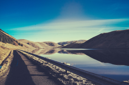 Retro Filtered Scenic Landscape Of An Empty Road By A Lake In Scotlandの写真素材