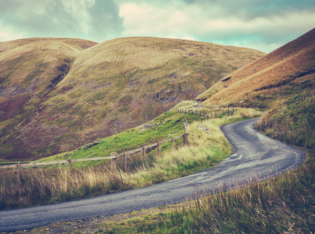 Winding Single Lane Road Up Through The Rugged Landscape Of The Scottish Bordersの写真素材