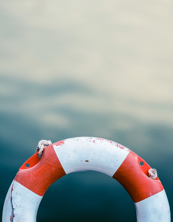 Grungy Lifebuoy Against A Calm Ocean Water Background With Copy Spaceの写真素材
