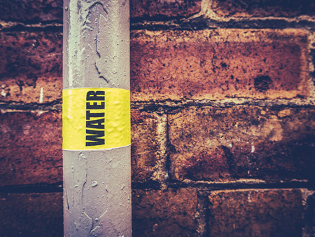 Detail Of An External Residential Water Pipe Against A Red Brick Wallの写真素材