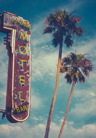 Retro Worn Vintage Neon Motel Sign And Palm Treesの写真素材