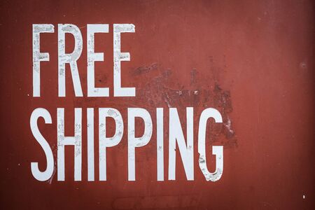 Grungy Free Shipping Sign On The Side Of A Red Metal Shipping Containerの写真素材