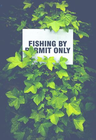 Fishing By Permit Only Sign Hidden In The Foliage By A Scottish Riverの写真素材