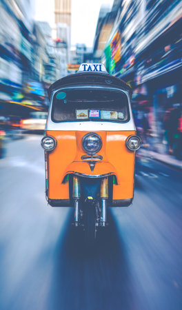 A Tuk-Tuk Taxi Racing Along A Busy Street In Bangkokの写真素材