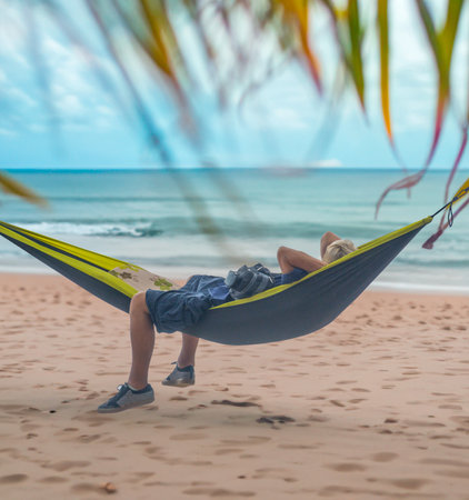 A Man Enjoying A Nap In A Hammock On A Beach In Hawaiiの写真素材