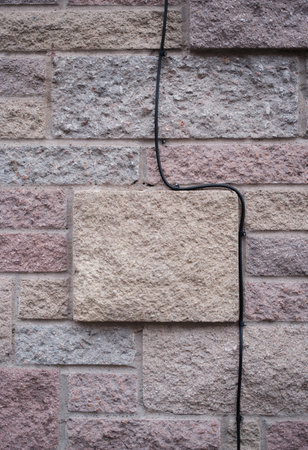 A Cable As It Is Routed Down A Stone Wall Outsideの写真素材