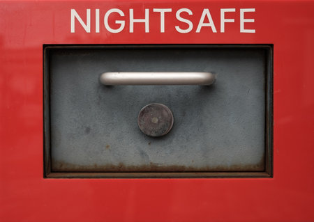 Close-Up Of A Bank Nightsafe Deposit Box With A Metal Handle And Lock On A Red Backgroundの写真素材