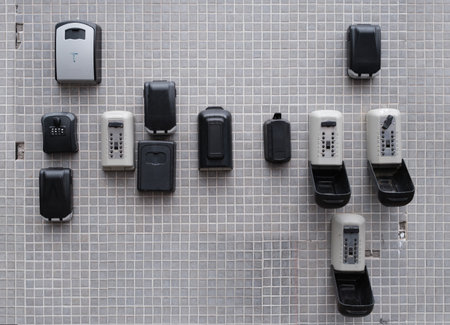 Multiple Key Lock Boxes Mounted On Outdoor Tiled Wall Used For Secure Storage And Access Control In Real Estate And Property Managementの写真素材