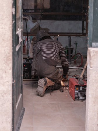 Worker Welding Metal With Protective Gear And Sparks Flying In Workshopの写真素材