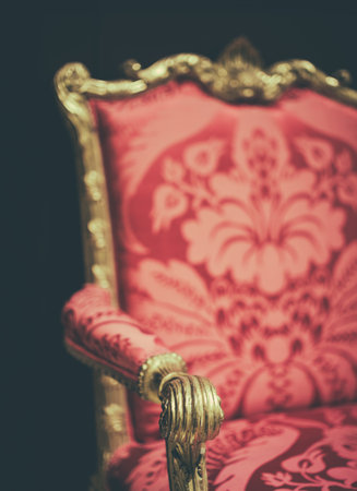 Close-Up Of A Luxurious Antique Armchair Or Throne With Golden Carved Details And Red Patterned Upholstery In Baroque Styleの写真素材