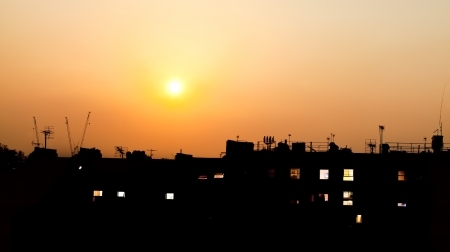 Sunset over rooftops with building lightsの写真素材