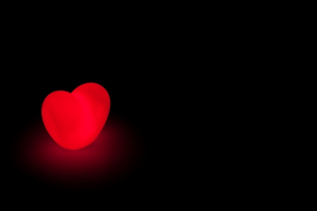 Glowing love haeart on black background with copy spaceの写真素材