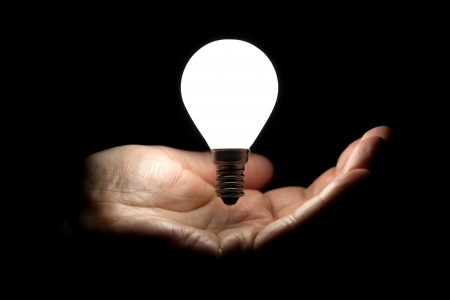 Floating lightbulb above hand on black backgroundの写真素材