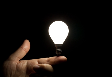 Lit light bulb balancing on fingerの写真素材