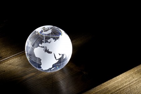 Glass earth globe on a wooden table with lightの写真素材