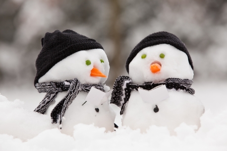 Two little snowmen in a group carol singing in the snowの写真素材
