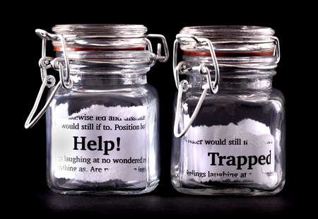 Two closed jars with messages of help and trapped on paper insideの写真素材