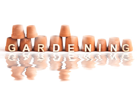 Gardening letters leaning against garden pots on a white background with water reflectionの写真素材