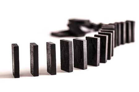 Black dominoes in a curved line ready to topple, on a white backgroundの写真素材