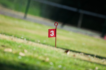 Golf course hole three flag, viewed from a low angle and shallow depth of fieldの写真素材