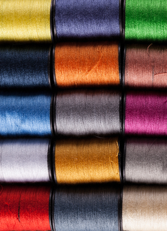 Colorful cotton reels lined up in a row and viewed from aboveの写真素材