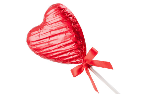 Red Chocolate love heart lollypop with a red ribbon bow on a stick. Isolated on a white background angledの写真素材