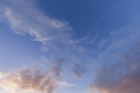 Great wispy clouds and blue sky background. Early morning sunlight with pink coloursの写真素材