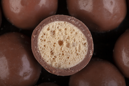 Chocolate honeycomb sweets cut in half closeup. High sugar food representing non diet occasional treat only foods in macro.の写真素材