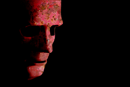 Old robotic decaying face mask. Rusty red grunge texture on a black background with copy space.の写真素材
